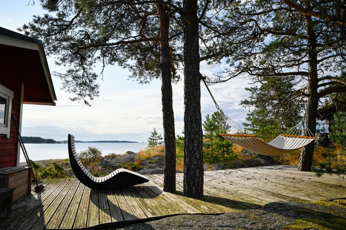 Trädäck bland tallar vid havet med en solstol i kvällsljus